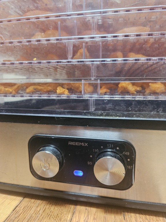 A dehydrator with trays full of peppers, set to 167 degrees